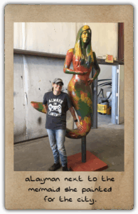 aLayman next to the mermaid she painted for the city